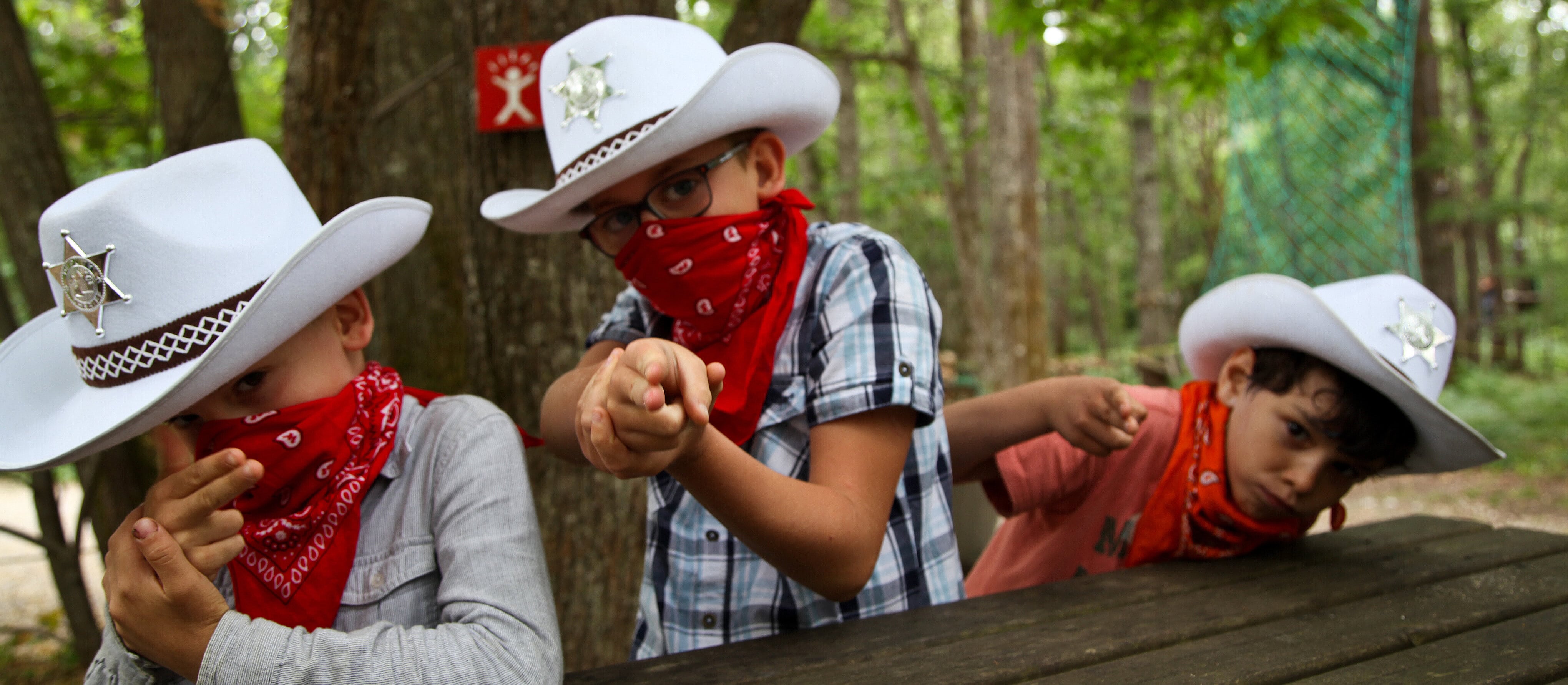 des enfants qui jouent aux cow boys en colonie de vacances l'été