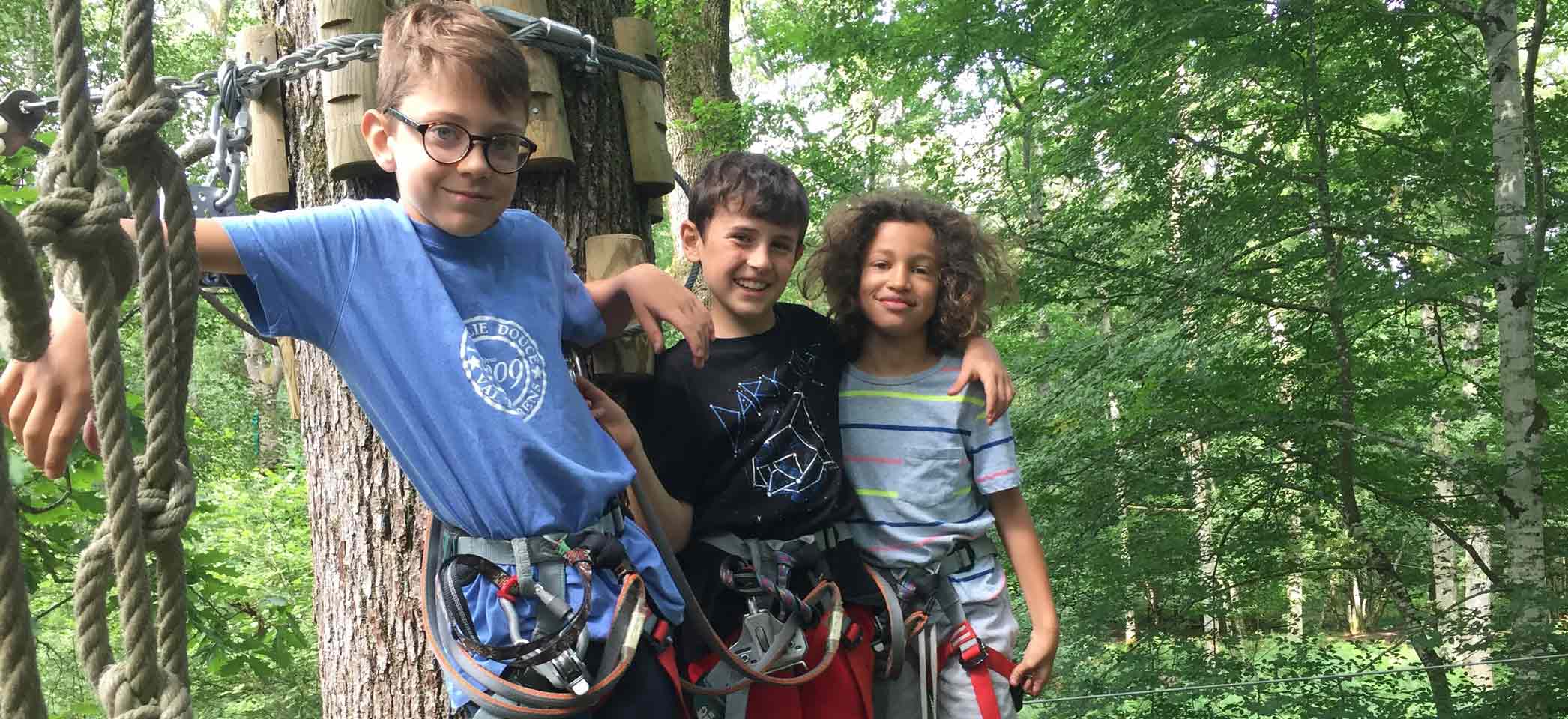 Groupe d'enfants de 7 ans sur une colo de vacances à la campagne profitant des activités extérieures comme l'accrobranche pendant la saison d'été en France